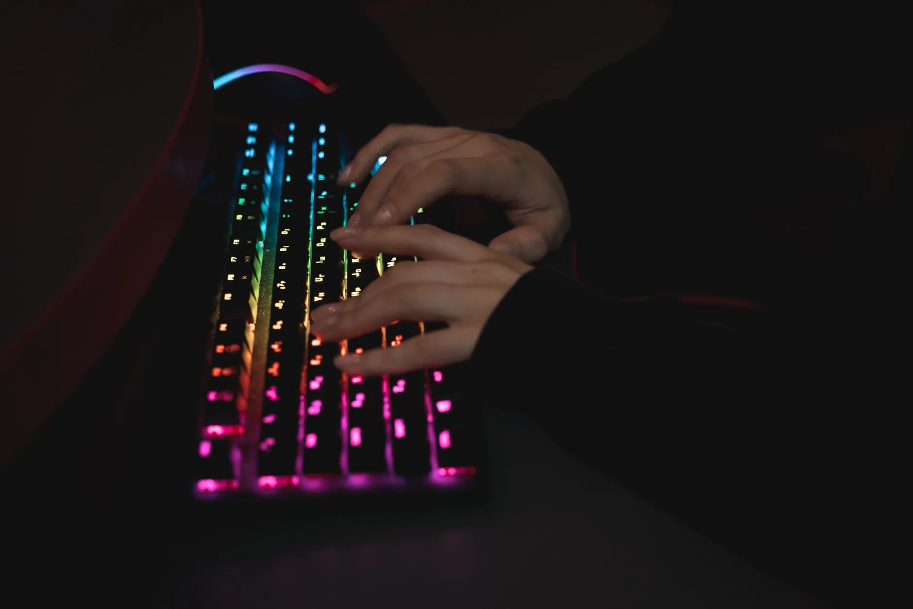 hands typing on a backlit mechanical keyboard in a dim room